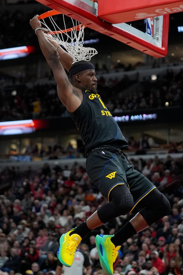 Golden State Warriors forward Jimmy Butler hangs from the rim after dunking during the second half of an NBA basketball game against the Chicago Bulls, Saturday, Feb. 8, 2025, in Chicago. (AP Photo/Erin Hooley)