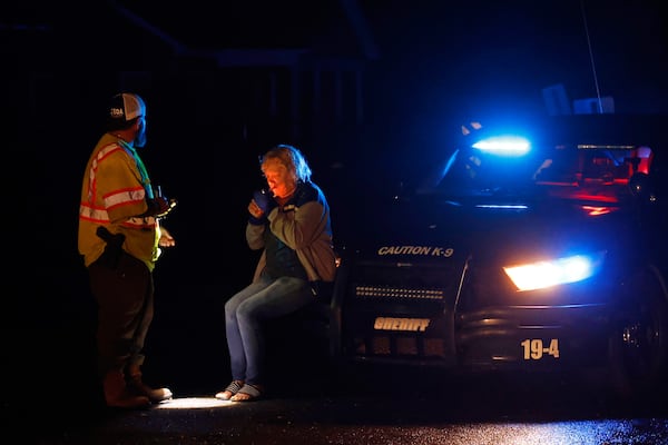 Michelle Moore is tended to by a police officer after she was rescued by her son who pulled her out of her trailer that was destroyed by a tornado that passed through, Saturday, March 15, 2025, in Plantersville, Ala. (AP Photo/Butch Dill)