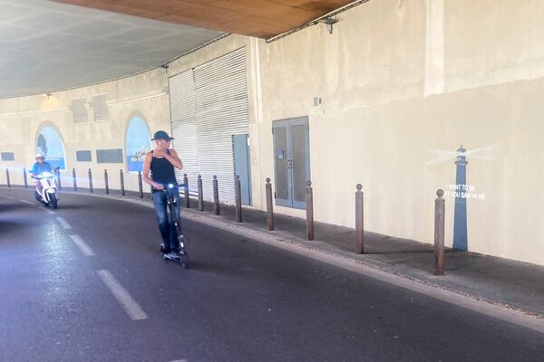 A man rides his scooter by an artwork by street artist Banksy, Friday, May 30, 2025 in Marseille, southern France. (AP Photo/Bishr Eltoni)