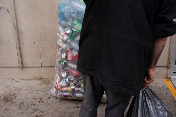 A person holds a bag of used beverage containers while waiting outside the Glisan BottleDrop Redemption Center on Thursday, May 15, 2025, in Portland, Ore. (AP Photo/Jenny Kane)