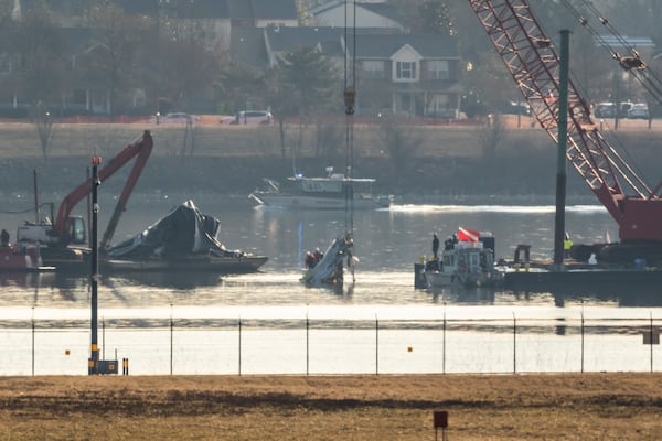 Salvage crews lift a piece of wreckage from the water at the site in the Potomac River of a mid-air collision between an American Airlines jet and a Black Hawk helicopter, at Ronald Reagan Washington National Airport, Tuesday, Feb. 4, 2025, in Arlington, Va. (AP Photo/Ben Curtis)