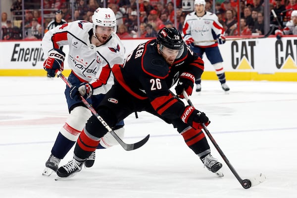 Carolina Hurricanes' Sean Walker (26) controls the puck in front of Washington Capitals' Connor McMichael (24) during the first period of Game 4 of a second-round NHL hockey playoff series in Raleigh, N.C., Monday, May 12, 2025. (AP Photo/Karl DeBlaker)
