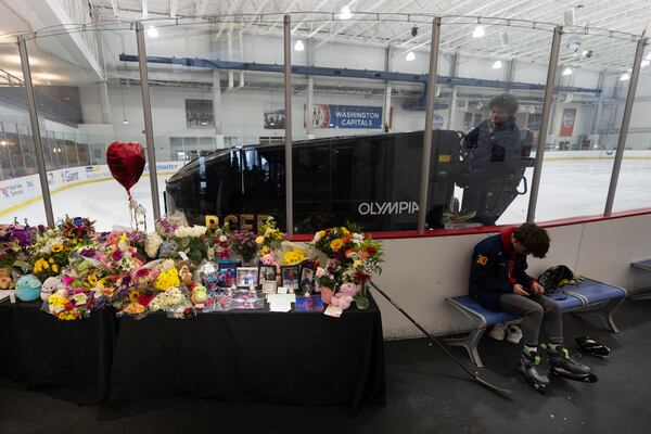 An ice resurfacer prepares the ice as a memorial is seen along the boards at MedStar Capitals Iceplex Sunday, Feb. 2, 2025, in Arlington, Va., for the figure skaters who were among the 67 victims of a mid-air collision between an Army helicopter and an American Airlines flight from Kansas. (AP Photo/Carolyn Kaster)