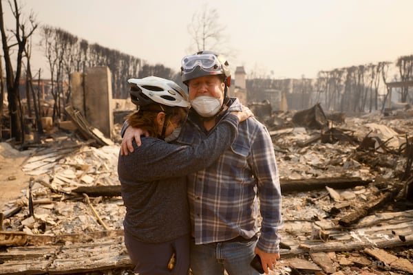 Claudio and Kathleen Boltiansky embrace in their fire-ravaged neighborhood after the Palisades Fire swept through in the Pacific Palisades neighborhood of Los Angeles, Wednesday, Jan. 8, 2025. (AP Photo/Etienne Laurent)