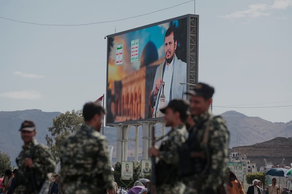 Houthi security officers stand next to a street billboard displaying a picture of Abdul Malik al-Houthi, the leader of the Houthi movement, in Sanaa, Yemen, Monday, March 17, 2025. (AP Photo/Osamah Abdulrahman)