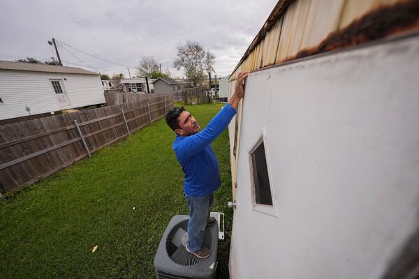 Mario Mendoza works on repairing a mobile home in Belle Chasse, La., Wednesday, Jan. 15, 2025, that was damaged from Hurricane Ida in 2021. (AP Photo/Gerald Herbert)