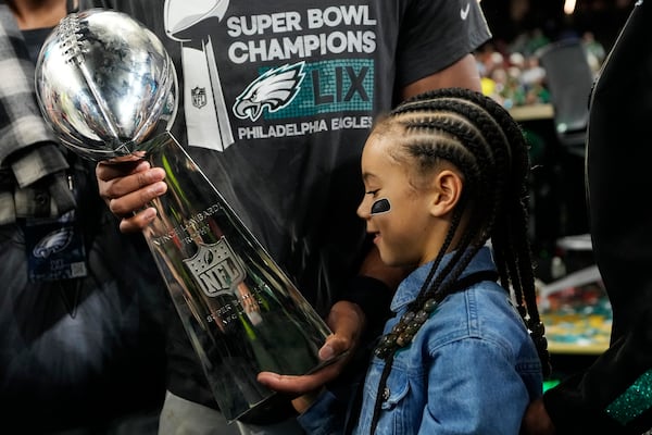 Philadelphia Eagles running back Saquon Barkley's daughter Jada looks at the Vince Lombardi Trophy after the NFL Super Bowl 59 football game against the Kansas City Chiefs, Sunday, Feb. 9, 2025, in New Orleans. (AP Photo/Ashley Landis)