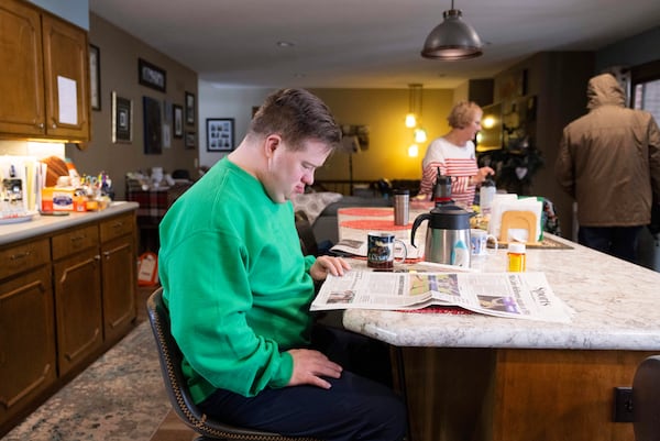 Paul Safarik, 32, reads the newspaper with a cup of coffee by his side on Wednesday, Feb. 12, 2025, in Lincoln, Neb. (AP Photo/Rebecca S. Gratz)