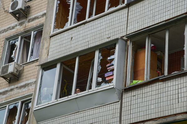 A resident looks out of the broken window in an apartment house following Russia's drone attack in Kyiv, Ukraine, Sunday, May 4, 2025. (AP Photo/Efrem Lukatsky)