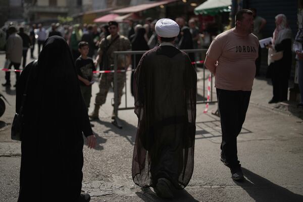 A Shiite cleric arrives to vote at a polling station as Lebanese army soldiers secure the area during municipal elections in the southern suburbs of Beirut, Lebanon, Sunday, May 4, 2025. (AP Photo/Hassan Ammar)