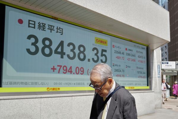 A person walks in front of an electronic stock board showing Japan's Nikkei index at a securities firm Tuesday, May 13, 2025, in Tokyo. (AP Photo/Eugene Hoshiko)