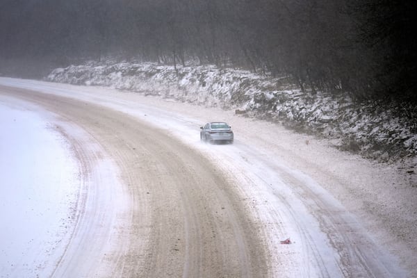 A car slowly navigates a snow-covered interstate Sunday, Jan. 5, 2025, in St. Louis. (AP Photo/Jeff Roberson)