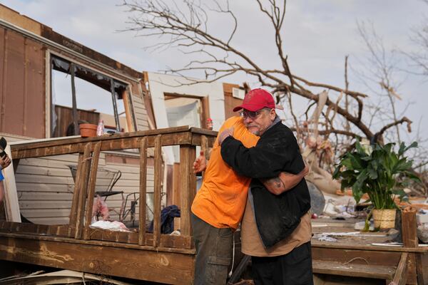 Tim Scott, right, gets a hug from friend Jorden Harris outside Scott's home he was inside when it was destroyed during a severe storm the evening before Saturday, March 15, 2025, in Wayne County, Mo. (AP Photo/Jeff Roberson)