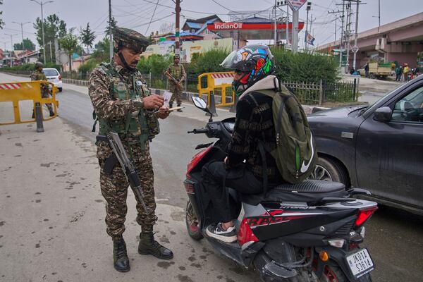 Indian paramilitary soldier checks the identity card of a scooterist at a temporary check point on the road leading to the airport after loud explosions were heard in Srinagar, in Indian controlled Kashmir, Saturday, May 10, 2025. (AP Photo/Dar Yasin)