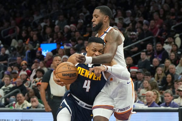 Denver Nuggets guard Russell Westbrook (4) drives on Phoenix Suns forward Royce O'Neale during the first half of an NBA basketball game, Wednesday, Dec. 25, 2024, in Phoenix. (AP Photo/Rick Scuteri)