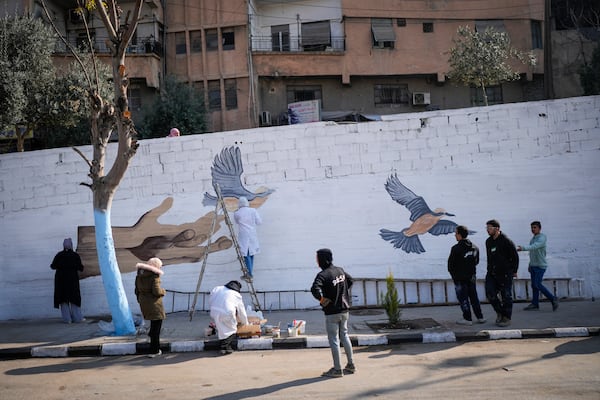 A group of young volunteers paints a mural symbolizing peace on a wall on the outskirts of Damascus, Syria, Sunday, Jan. 12, 2025. (AP Photo/Mosa'ab Elshamy)