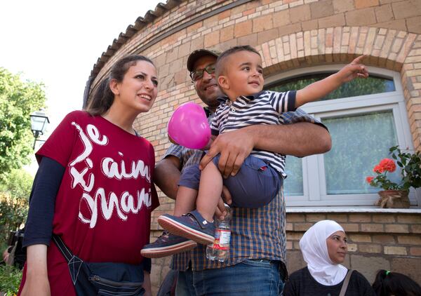 FILE - Syrian refugee Nour Essa, second from right, her husband Hasan Zaheda and their one-year-old son Riad smile during an interview with the Associated Press at the St. Egidio Roman Catholic Charity, in Rome, Sunday, April 17, 2016. (AP Photo/Alessandra Tarantino, File)