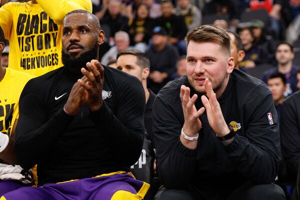 Los Angeles Lakers guard Luka Doncic, right, sits next to forward LeBron James on the bench before an NBA basketball game against the Los Angeles Clippers, Tuesday, Feb. 4, 2025, in Inglewood, Calif. (AP Photo/Kevork Djansezian)