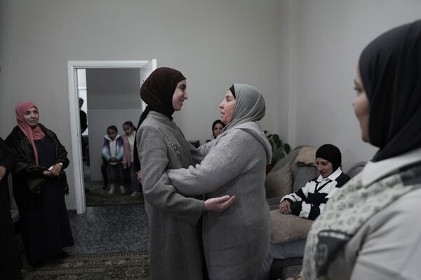 Amal Shujaeiah, a former Palestinian prisoner who was released from an Israeli prison as part of a ceasefire deal between Israel and Hamas, embraces relatives at her home in Dayr Jarir, West Bank, Monday, Jan. 20, 2025. (AP Photo/Mahmoud Illean)