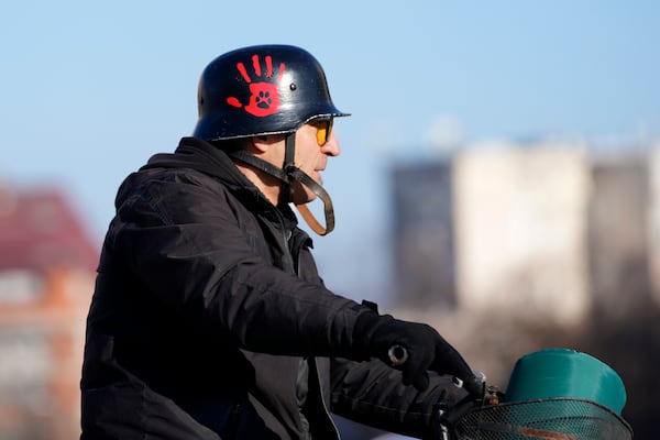 A man wearing a helmet painted with a red hand, a symbol representing the government's bloody hands, rides a bicycle during a protest over the collapse of a concrete canopy that killed 15 people more than two months ago, in Novi Sad, Serbia, Saturday, Feb. 1, 2025. (AP Photo/Darko Vojinovic)