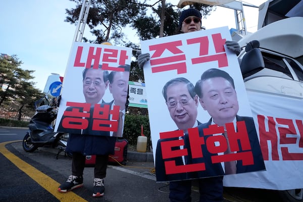 Protesters hold banners showing images of impeached President Yoon Suk Yeol, right, and acting President Han Duck-soo during a rally demanding Han's impeachment outside of the National Assembly in Seoul, South Korea, Dec. 27, 2024. The signs read "Impeachment immediately" (AP Photo/Ahn Young-joon)