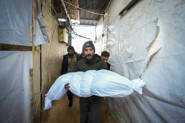 The body of a victim of an Israeli army strike on a house in the Bureij refugee camp is carried for the funeral at the Al-Aqsa Martyrs Hospital in the central Gaza Strip town of Deir al-Balah Wednesday, Jan. 1, 2025. (AP Photo/Abdel Kareem Hana)