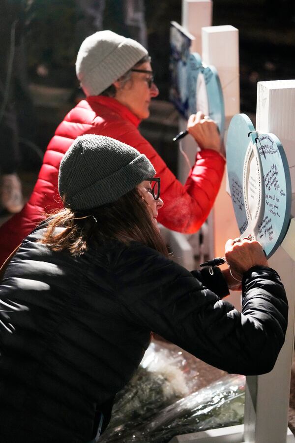 Supporters sign crosses during a candlelight vigil Tuesday, Dec. 17, 2024, outside the Wisconsin Capitol in Madison, Wis., following a shooting at the Abundant Life Christian School on Monday, Dec. 16. (AP Photo/Morry Gash)