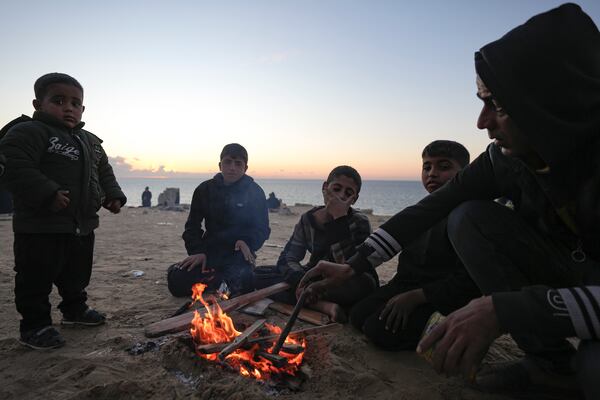 Displaced Palestinians warm themselves by a fire near a roadblock, as they wait to return to their homes in the northern part of the Gaza Strip, Sunday, Jan. 26, 2025, days after the ceasefire deal between Israel and Hamas came into effect. (AP Photo/Abdel Kareem Hana)