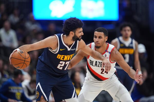 Denver Nuggets guard Jamal Murray, left, looks to pass the ball as Portland Trail Blazers forward Kris Murray defends in the second half of an NBA basketball game Wednesday, Feb. 12, 2025, in Denver. (AP Photo/David Zalubowski)