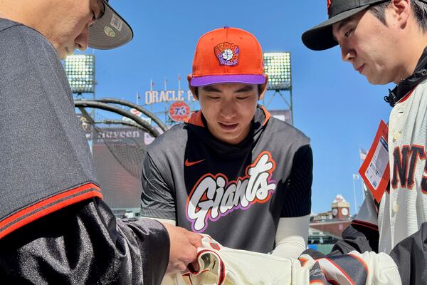 San Francisco Giants' Jung Hoo Lee, middle, signs autographs for fans before a baseball game between the Giants and the Arizona Diamondbacks in San Francisco, Tuesday, May 13, 2025. (AP Photo/Haven Daley)