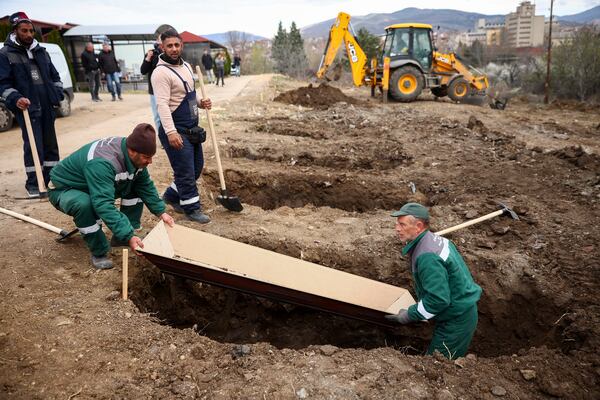 Municipal workers use an empty coffin to measure the graves they are digging for the victims of a massive nightclub fire, in the town of Kocani, North Macedonia, Tuesday, March 18, 2025. (AP Photo/Armin Durgut)