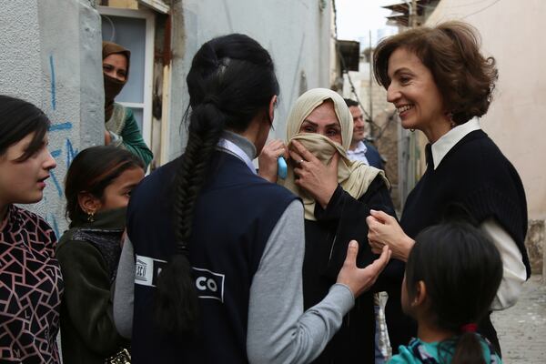 UNESCO Director-General Audrey Azoulay, right, speaks to women and children as she visits historic sites in Mosul, Iraq, Wednesday, Feb. 5, 2025, reconstructed by UNESCO after being damaged in battles with the Islamic State group when it held the city. (AP Photo/Farid Abdulwahed)