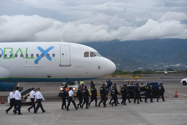 Security personnel approach a plane carrying migrants from Central Asia and India, deported from the United States, at Juan Santamaría International Airport in San Jose, Costa Rica, Thursday, Feb. 20, 2025. (AP Photo/Jose Diaz)