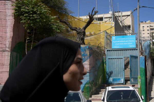A woman passes the front entrance to the UNRWA Boys' School run by the U.N. agency for Palestinian refugees in the Shuafat Refugee Camp in east Jerusalem, Tuesday, April 29, 2025. (AP Photo/Maya Alleruzzo)
