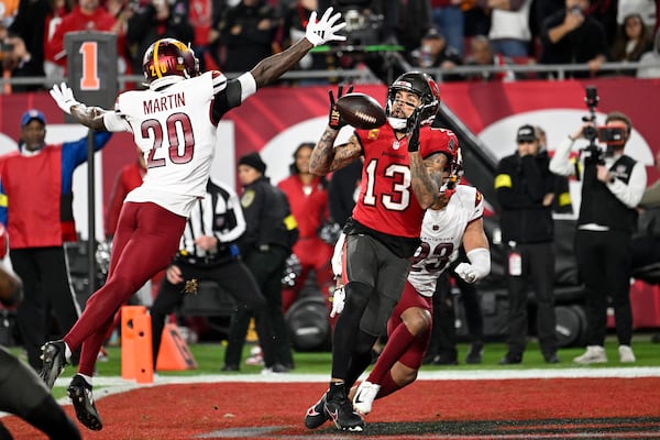 Tampa Bay Buccaneers wide receiver Mike Evans (13) catches a touchdown pass against Washington Commanders Quan Martin (20) and cornerback Marshon Lattimore (23) during the first half of an NFL wild-card playoff football game in Tampa, Fla., Sunday, Jan. 12, 2025. (AP Photo/Jason Behnken)