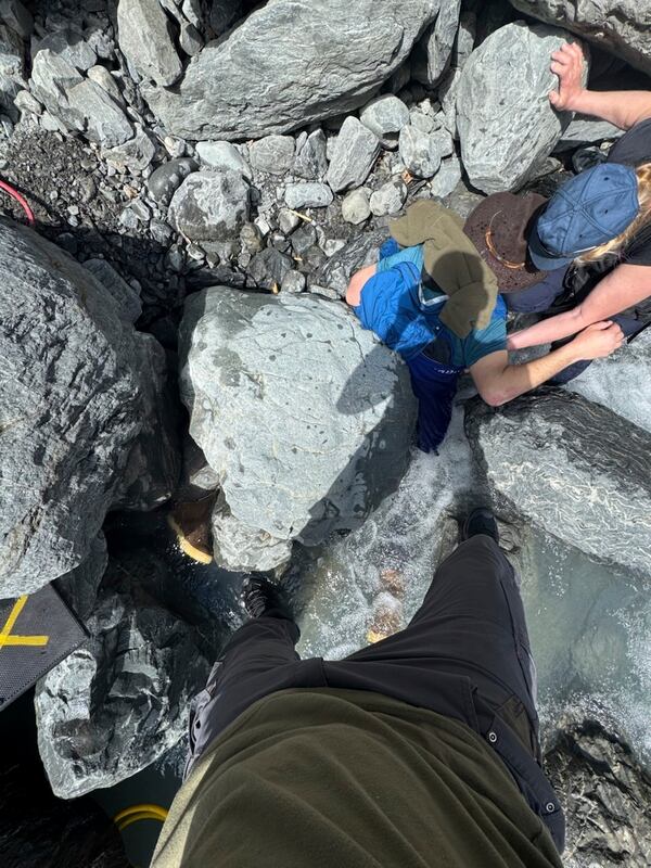 This May 24, 2025, photo shows Kell Morris, upper right in a brown hat, trapped under a 700 pound rock near Seward, Alaska. (Jason Harrington/Seward Fire Department via AP)