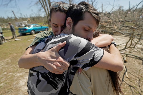 Steve Romero, 23, center, hugs his wife, Hailey Hart, right, and their friend Jessica Soileau, left, after recalling how he, his fiancee and their three dogs rode out Saturday's tornado in their small 1994 Toyota in Tylertown, Miss., on Sunday, March 16, 2024. (AP Photo/Rogelio V. Solis)