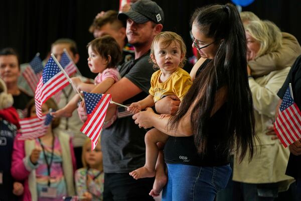 Afrikaner refugees from South Africa holding American flags arrive, Monday, May 12, 2025, at Dulles International Airport in Dulles, Va. (AP Photo/Julia Demaree Nikhinson)