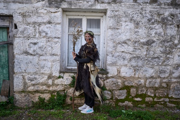 Vaso Statha, 15 poses for a portrait, dressed in animal skins and heavy bronze bells, as part of carnival celebrations in Distomo, a village in central Greece, on Monday, March 3, 2025. (AP Photo/Petros Giannakouris)