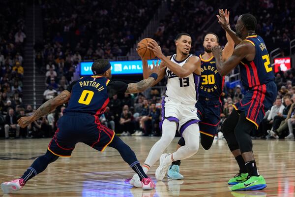 Sacramento Kings forward Keegan Murray (13) moves the ball between Golden State Warriors guards Gary Payton II (0) and Stephen Curry (30) during the first half of an NBA basketball game Thursday, March 13, 2025, in San Francisco. (AP Photo/Godofredo A. Vásquez)