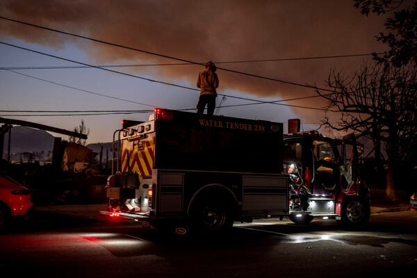 Lucas Hirst, a firefighter with San Ramon Valley Fire Protection District, is seen on top of a water tender during sunset at the Palisades Fire in Pacific Palisades, Calif., Friday, Jan. 10, 2025. (Stephen Lam/San Francisco Chronicle via AP)