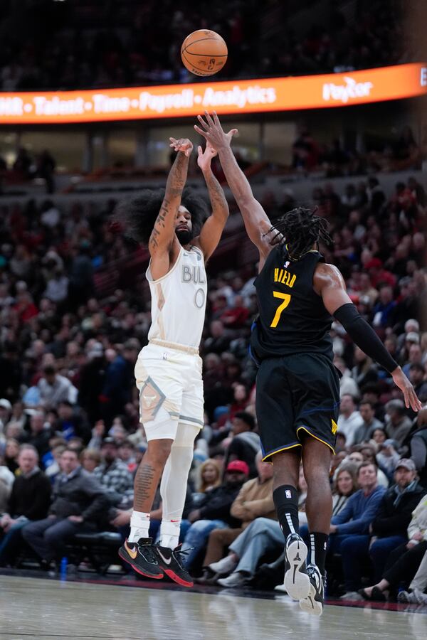 Golden State Warriors guard Buddy Hield (7) tries to block Chicago Bulls guard Coby White (0) who shoots a 3-point basket during the first half of an NBA basketball game Saturday, Feb. 8, 2025, in Chicago. (AP Photo/Erin Hooley)