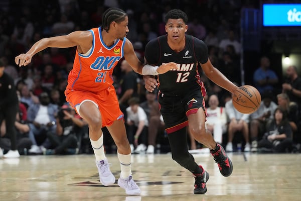 Miami Heat guard Dru Smith (12) dribbles the ball as Oklahoma City Thunder guard Aaron Wiggins (21) defends during the first half of an NBA basketball game, Friday, Dec. 20, 2024, in Miami. (AP Photo/Marta Lavandier)