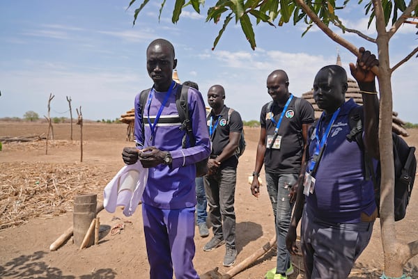 Aid workers with the Carter Center work in the community to raise awareness about Guinea worm and a family impacted in Jarweng, South Sudan, on May 13, 2023. (AP Photo/Sam Mednick)