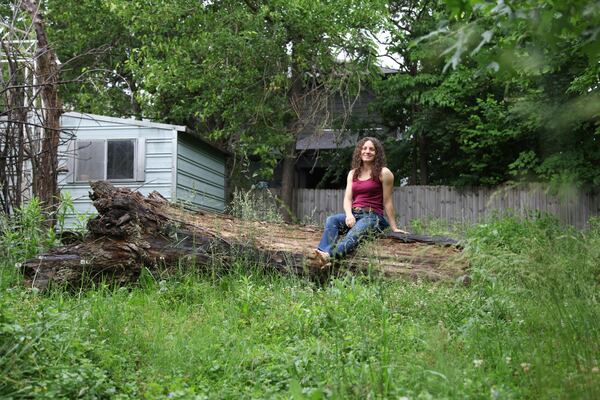 Amanda Beltranmini Healen poses on a fallen log in her backyard in Nashville, Tenn., Monday, May 19, 2025, where she participates in No Mow Months to improve water retention and encourage pollinators. (AP Photo/Kristin M. Hall)