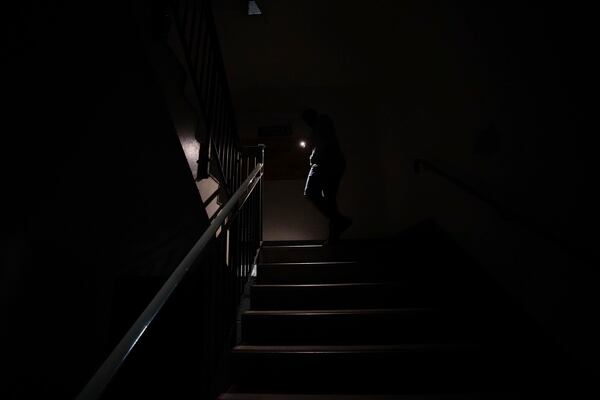 Stranded passengers makes their way down unlit stairs due to lifts not working to the car park at Heathrow Terminal 4 in London, Friday March 21, 2025, as consequence of the closure of the airport following a fire at the North Hyde electrical substation last night. (James Manning/PA via AP)