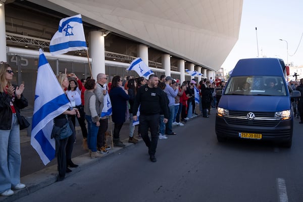 People attend a public memorial ceremony for slain hostage Tsachi Idan, a fan of Hapoel Tel Aviv F.C., who was killed in Hamas captivity in the Gaza Strip, watch a van carrying his coffin outside of Bloomfield Stadium in Tel Aviv, Israel, Friday, Feb. 28, 2025. (AP Photo/Leo Correa)