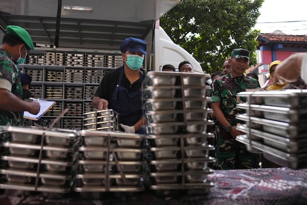 Workers unload food containers to be distributed to classrooms during the kick off of President Prabowo Subianto's ambitious free meal program to feed children and pregnant women nationwide despite critics saying that its required logistics could hurt Indonesia's state finances and economy, at an elementary school in Depok, West Java, Indonesia, Monday, Jan. 6, 2025. (AP Photo/Dita Alangkara)