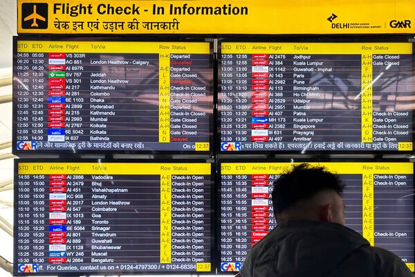 A passenger stands in front of a flight information screen showing cancelled flights destined for the Heathrow Airport in London, at the Indira Gandhi International Airport, in New Delhi, India, Friday, March 21, 2025. (AP Photo/Shonal Ganguly)