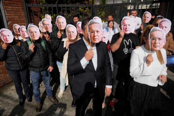 Supporters of Colombia's former President Alvaro Uribe hold cutouts of his portrait outside the court where he is attending a hearing on charges of witness tampering and bribery in Bogota, Colombia, Monday, Feb. 10, 2025. (AP Photo/Fernando Vergara)